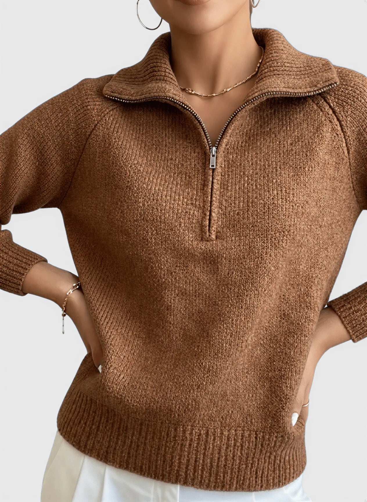 A professional model wears Nuvé’s brown knitted sweater with a zipper, showcased on a clean, plain background for a timeless, sophisticated look.