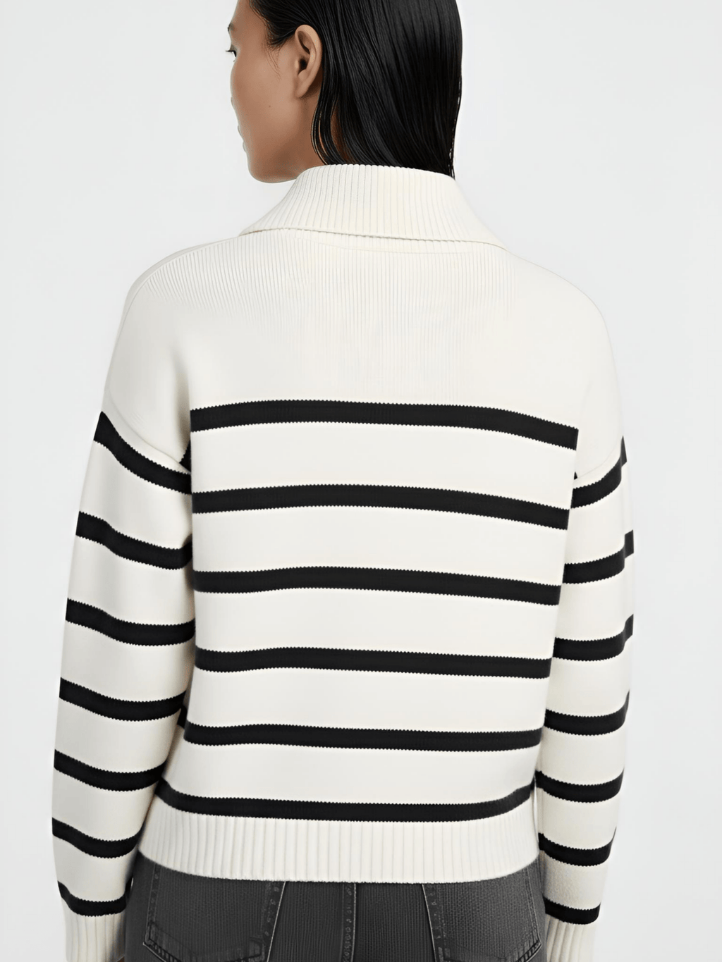 Person wearing a white sweater with black horizontal stripes on a plain background