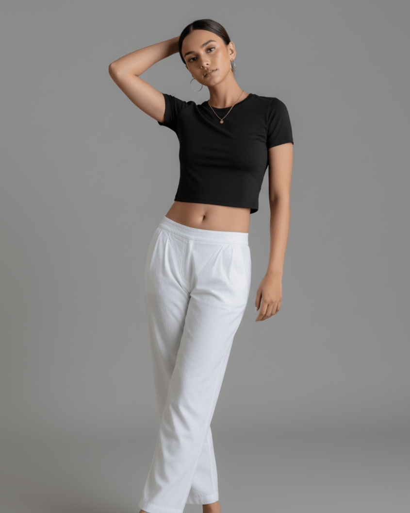 Woman wearing a black crop top and white pants on a gray background