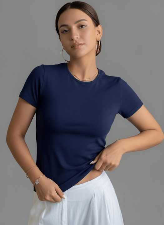 Woman wearing a navy blue t-shirt and white pants against a gray background